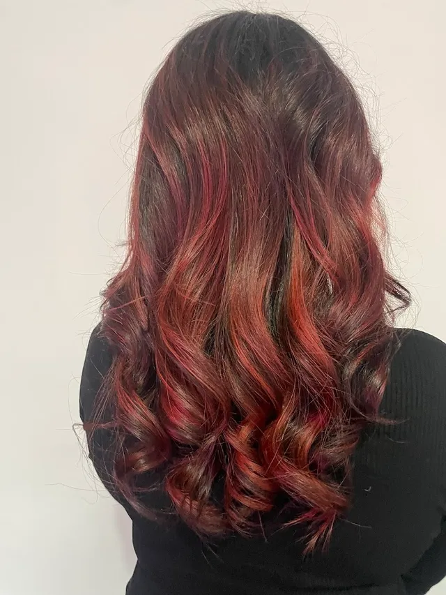 Rich copper-and-red balayage curled through the ends